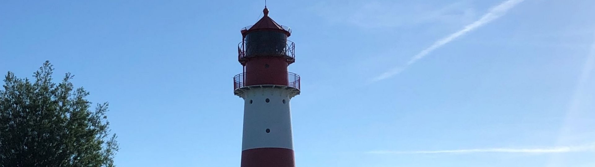 Rot-weißer Leuchtturm in grüner Umgebung