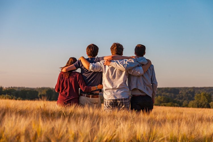 4 mit dem Rücken zu uns sitzende sich umarmende Kinder